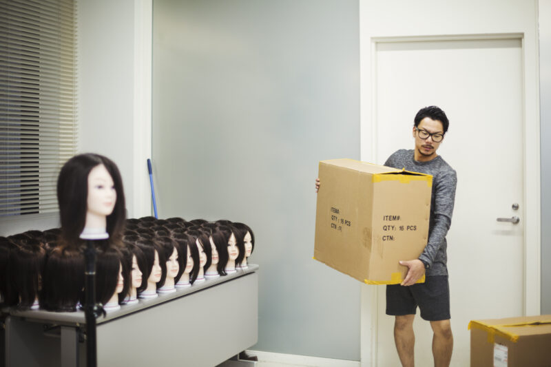 Man carrying a box in a wig shop